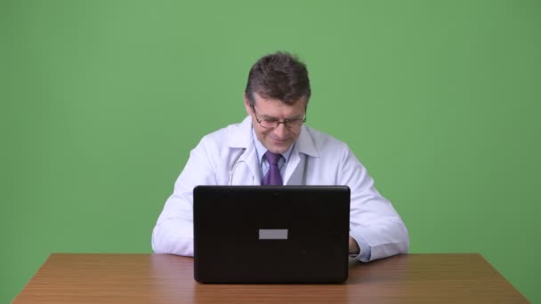 Зрелый красивый мужчина врач на зеленом фоне — стоковое видео