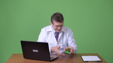 Olgun yakışıklı adam doktor yeşil bir arka plana dayanır