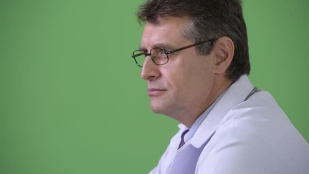 Зрелый красивый мужчина врач на зеленом фоне — стоковое видео