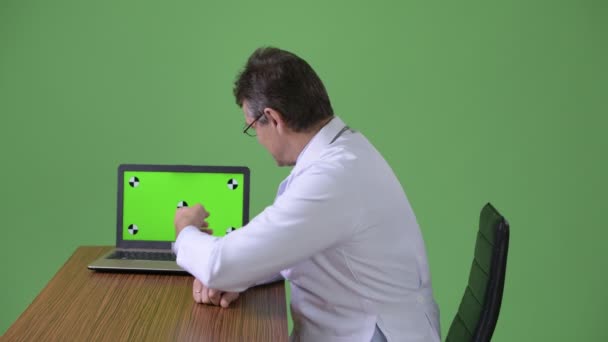 Volwassen knappe man arts tegen groene achtergrond — Stockvideo