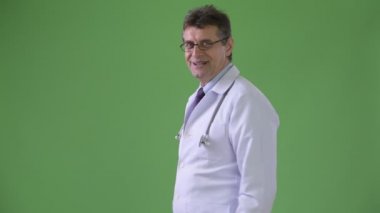 Olgun yakışıklı adam doktor yeşil bir arka plana dayanır