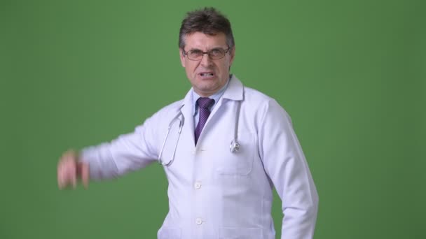 Volwassen knappe man arts tegen groene achtergrond — Stockvideo