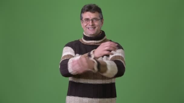 Зрілий красивий чоловік у жахливому светрі на зеленому тлі — стокове відео