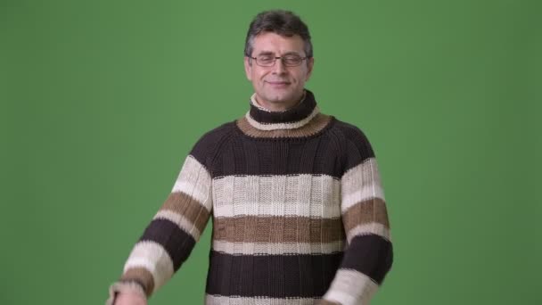 Äldre stilig man polokrage tröja mot grön bakgrund — Stockvideo