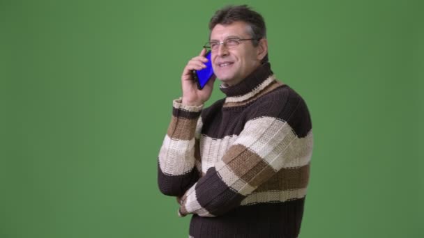 Mature handsome man wearing turtleneck sweater against green background — Stock Video