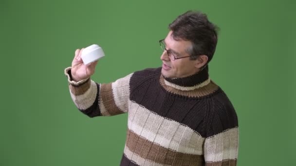 Älterer gutaussehender Mann trägt Rollkragenpullover vor grünem Hintergrund — Stockvideo