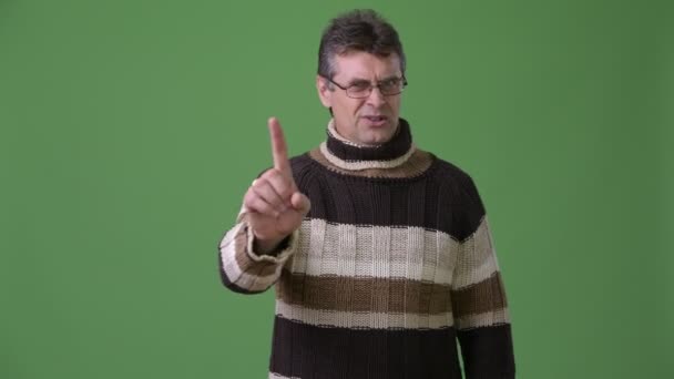 Yeşil bir arka plana dayanır boğazlı kazak giyen Olgun yakışıklı adam — Stok video