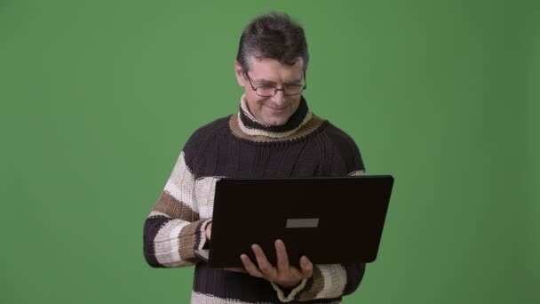 Érett jóképű férfi viselt magas nyakú pulóvert zöld háttér — Stock videók