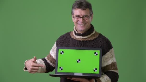 Зрелый красивый мужчина в свитере в водолазке на зеленом фоне — стоковое видео