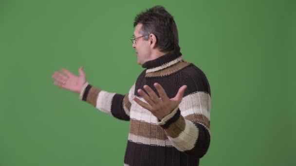 Volwassen knappe man dragen coltrui trui tegen groene achtergrond — Stockvideo