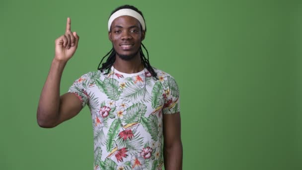 Joven hombre africano guapo con rastas sobre fondo verde — Vídeo de stock