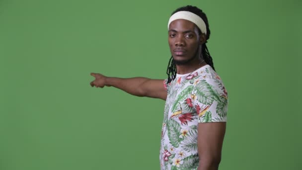 Young handsome African man with dreadlocks against green background — Stock Video