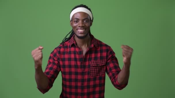 Junger schöner afrikanischer Mann mit Dreadlocks vor grünem Hintergrund — Stockvideo