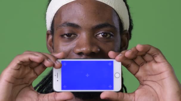 Jonge knappe man van de Afrikaanse met dreadlocks tegen groene achtergrond — Stockvideo