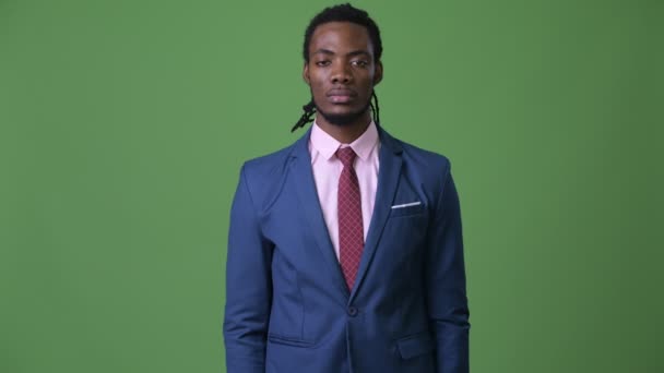 Jonge knappe Afrikaanse zakenman met dreadlocks tegen groene achtergrond — Stockvideo