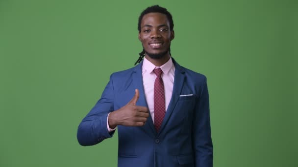 Joven hombre de negocios africano guapo con rastas sobre fondo verde — Vídeo de stock