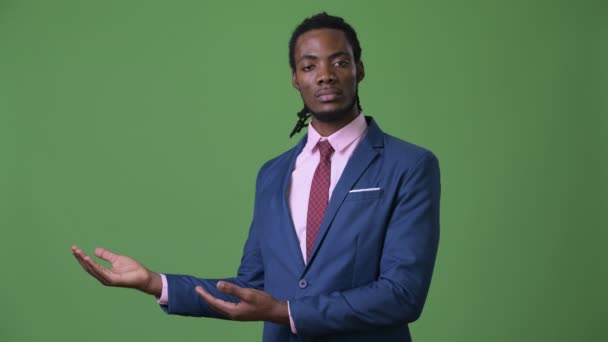 Joven hombre de negocios africano guapo con rastas sobre fondo verde — Vídeo de stock