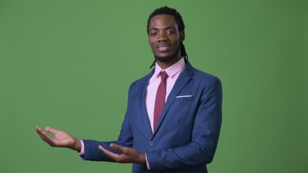 Joven hombre de negocios africano guapo con rastas sobre fondo verde — Vídeo de stock