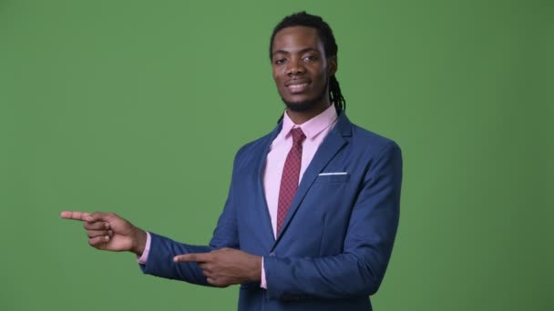 Jonge knappe Afrikaanse zakenman met dreadlocks tegen groene achtergrond — Stockvideo