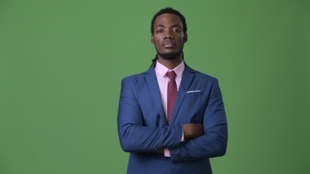 Junger schöner afrikanischer Geschäftsmann mit Dreadlocks vor grünem Hintergrund — Stockvideo