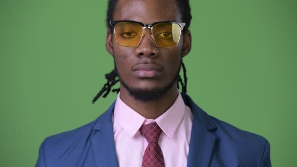 Joven hombre de negocios africano guapo con rastas sobre fondo verde — Vídeos de Stock