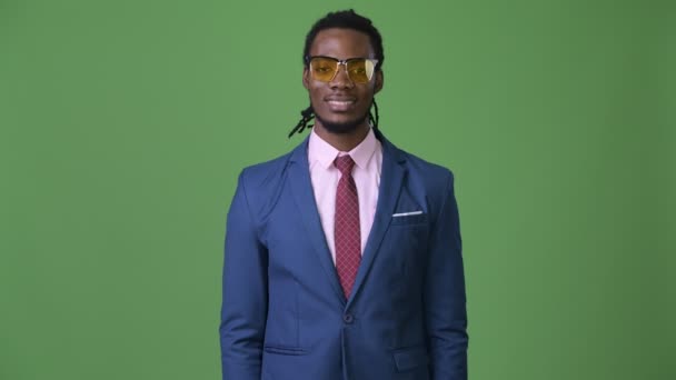 Yeşil bir arka plana dayanır dreadlocks ile genç yakışıklı Afrika iş adamı — Stok video