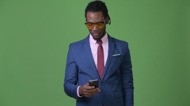 Joven hombre de negocios africano guapo con rastas sobre fondo verde — Vídeo de stock