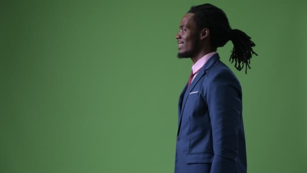 Young handsome African businessman with dreadlocks against green background — Stock Video
