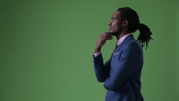 Joven hombre de negocios africano guapo con rastas sobre fondo verde — Vídeo de stock