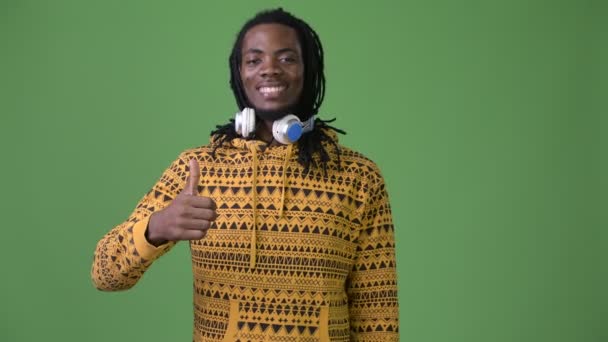 Young handsome African man with dreadlocks against green background — Stock Video