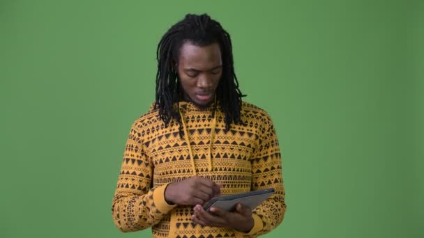 Young handsome African man with dreadlocks against green background — Stock Video