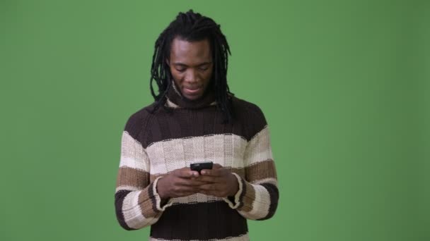 Young handsome African man with dreadlocks against green background — Stock Video