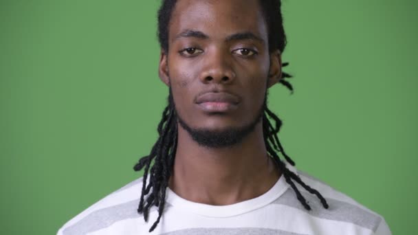 Jovem e bonito homem africano com dreadlocks contra fundo verde — Vídeo de Stock