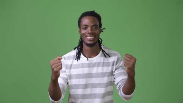 Joven hombre africano guapo con rastas sobre fondo verde — Vídeo de stock