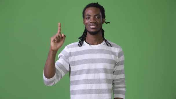 Junger schöner afrikanischer Mann mit Dreadlocks vor grünem Hintergrund — Stockvideo