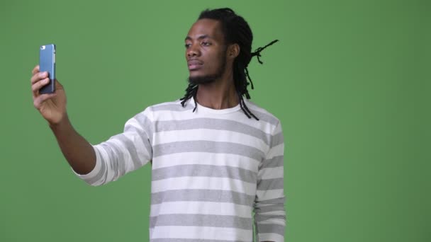 Joven hombre africano guapo con rastas sobre fondo verde — Vídeos de Stock