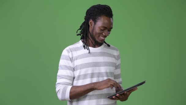 Young handsome African man with dreadlocks against green background — Stock Video