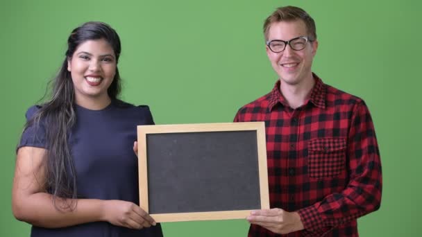 Jonge multi-etnische zaken paar samen tegen een groene achtergrond — Stockvideo