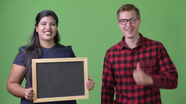 Jonge multi-etnische zaken paar samen tegen een groene achtergrond — Stockvideo