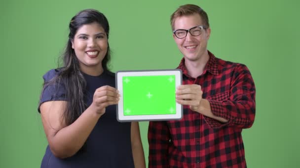 Молода багатоетнічна ділова пара разом на зеленому тлі — стокове відео