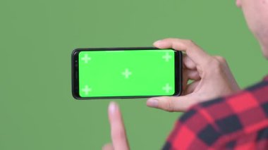 Genç İskandinav işadamı cep telefonuyla yeşil bir arka plana dayanır