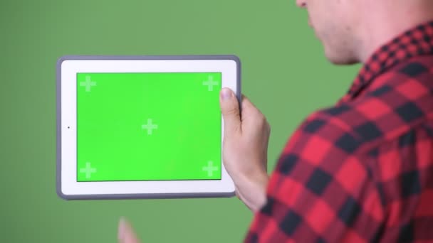 Joven hombre de negocios escandinavo usando tableta digital contra fondo verde — Vídeos de Stock