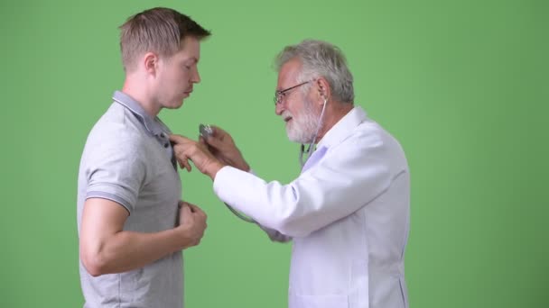 Homem barbudo sênior médico consultor homem paciente contra fundo verde — Vídeo de Stock