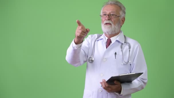 Bonito médico homem barbudo sênior contra fundo verde — Vídeo de Stock