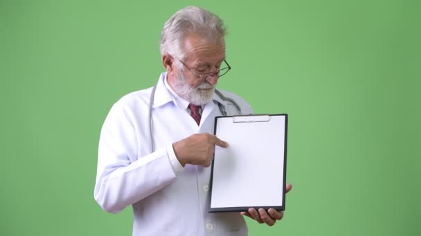 Bonito médico homem barbudo sênior contra fundo verde — Vídeo de Stock