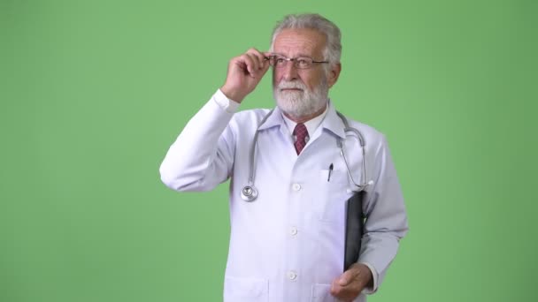 Przystojny starszy brodaty mężczyzna lekarz na zielonym tle — Wideo stockowe