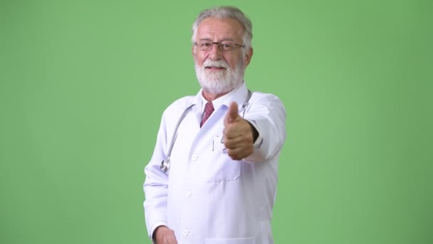 緑の背景にハンサムなシニアひげそりの男医師 — ストック動画