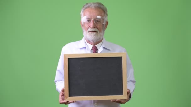 Guapo mayor barbudo médico hombre contra fondo verde — Vídeos de Stock