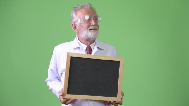 Przystojny starszy brodaty mężczyzna lekarz na zielonym tle — Wideo stockowe