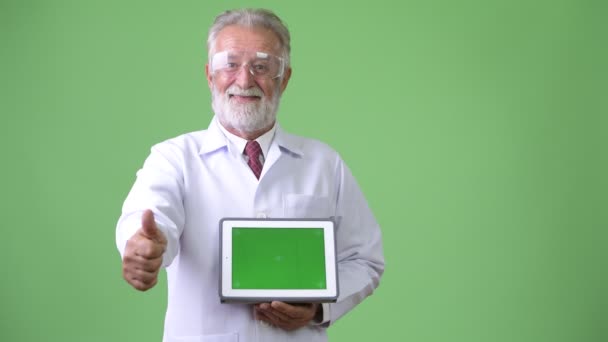 Красивий старший бородатий чоловік лікар на зеленому тлі — стокове відео